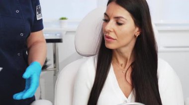 Güzellik kliniğindeki güzel esmer kadın. Oturup kadın doktorla yüz estetiği hakkında konuşuyor. Güvenilir ve mutlu..