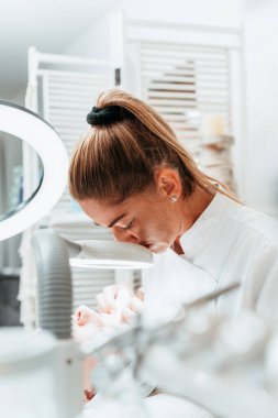 Modern donanımlı güzellik merkezinde profesyonel bir güzellik uzmanı genç bir kadının yüzündeki sivilceleri ve sivilceleri elle temizliyor. Yüz Temizleme. Güzelleştirme ve cilt sağlığı kavramı.