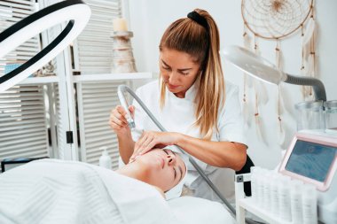 Genç bir kadın deri dökülmesi, yenilenmesi ve yüz derisinin sulanması için Hydra yüz tedavisi görüyor. Modern yüz hidro mikro cilt temizleme güzellik prosedürü. Hidra elektrikli süpürge.. 