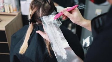 Kuaför kadın saçı boyuyor, müşterisine folyoyla saç renkleri yapıyor. Modern saç stili ve moda konsepti.