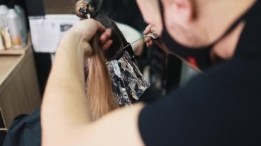 Kuaför kadın saçı boyuyor, müşterisine folyoyla saç renkleri yapıyor. Modern saç stili ve moda konsepti.