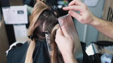Kuaför kadın saçı boyuyor, müşterisine folyoyla saç renkleri yapıyor. Modern saç stili ve moda konsepti.
