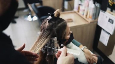Kuaför kadın saçı boyuyor, müşterisine folyoyla saç renkleri yapıyor. Modern saç stili ve moda konsepti.