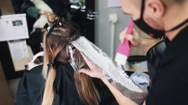 Kuaför kadın saçı boyuyor, müşterisine folyoyla saç renkleri yapıyor. Modern saç stili ve moda konsepti.