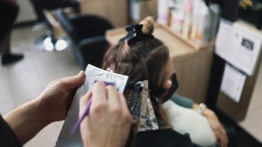 Kuaför kadın saçı boyuyor, müşterisine folyoyla saç renkleri yapıyor. Modern saç stili ve moda konsepti.