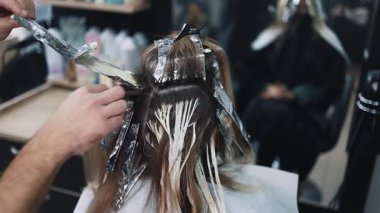 Kuaför kadın saçı boyuyor, müşterisine folyoyla saç renkleri yapıyor. Modern saç stili ve moda konsepti.