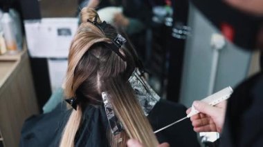 Kuaför kadın saçı boyuyor, müşterisine folyoyla saç renkleri yapıyor. Modern saç stili ve moda konsepti.