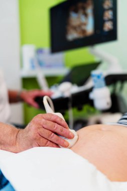 Doktor gebelik muayenesi sırasında hamilelik gelişimi ve sağlığını kontrol etmek için ultrason çevirici kullanıyor.