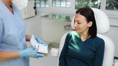 Güzellik kliniğindeki güzel esmer kadın. Oturup kadın doktorla yüz estetiği hakkında konuşuyor. Güvenilir ve mutlu..