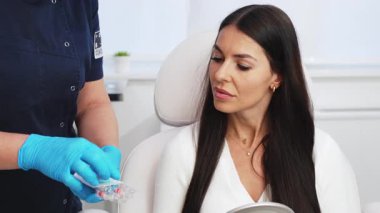 Güzellik kliniğindeki güzel esmer kadın. Oturup kadın doktorla yüz estetiği hakkında konuşuyor. Güvenilir ve mutlu..