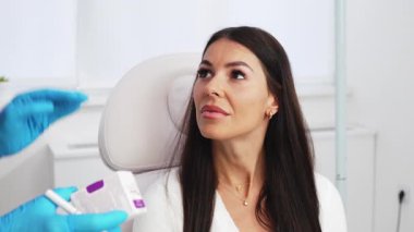 Güzellik kliniğindeki güzel esmer kadın. Oturup kadın doktorla yüz estetiği hakkında konuşuyor. Güvenilir ve mutlu..