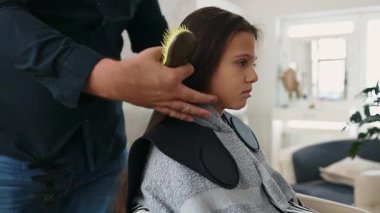 Profesyonel kuaför güzel bir kızın uzun kahverengi saçlarını ustalıkla kuruturken aynı zamanda canlı bir güzellik salonunda uzman saç bakım hizmeti veriyor.