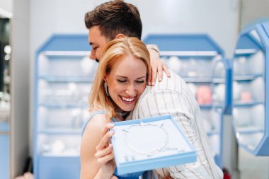 Mutlu genç çift kuyumcudan lüks mücevherler seçip almaktan zevk alıyor. Kadın mutlu ve heyecanlı..