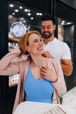 Mutlu çift bir kuyumcuda güzel bir mücevher parçası seçerken eğleniyor. İkisi de mutlu ve sevgi ve heyecanla gülümsüyor..