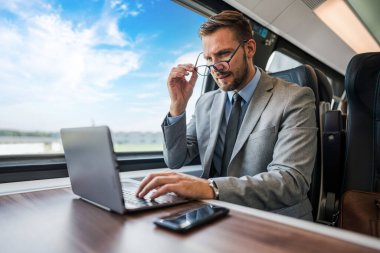 Tren yolculuğu sırasında dizüstü bilgisayarda çalışan yakışıklı bir iş adamı. Verimlilik için kullanılıyor.