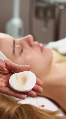 Güzellik uzmanı kadın hasta yüzüne nazikçe nemlendirici krem sürerek profesyonel spa ortamında rahatlatıcı ve canlandırıcı cilt bakımı sağlar.