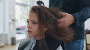 Profesyonel kuaför güzel bir kızın uzun kahverengi saçlarını ustalıkla kuruturken aynı zamanda canlı bir güzellik salonunda uzman saç bakım hizmeti veriyor.