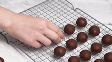 Profesyonel bir şekerci, hamur işi yaptıktan sonra beyaz bir ahşap tahtaya lezzetli çikolata şekerlemeleri yerleştiriyor, mermer bir masa üzerindeki metalik bir ızgarada daha fazla şekerleme soğutuluyor.