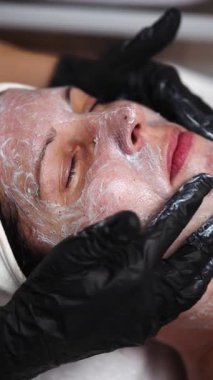 Güzellik uzmanı kadın hasta yüzüne nazikçe nemlendirici krem sürerek profesyonel spa ortamında rahatlatıcı ve canlandırıcı cilt bakımı sağlar.