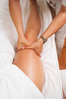 Profesyonel masöz, bir kaplıcada ya da sağlık merkezinde rahatlatıcı bir masaj seansı sırasında ellerini kadının bacağına bastırarak sağlık ve refahı teşvik ediyor.
