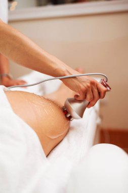 Profesyonel güzellik uzmanı, bir güzellik salonunda kadının bacağında cerrahi olmayan deri kaldırma tedavisi için modern bir cihaz kullanıyor. Gelişmiş esneklik ve dayanıklılık için gelişmiş cilt bakımı sağlıyor.