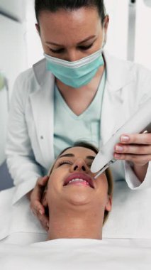 Profesyonel güzellik uzmanı koruyucu gözlüklü genç bir kadının dudaklarında ve çevresinde lazer tüyü temizleme tedavisi uyguluyor..