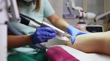 Profesyonel güzellik uzmanı, güzellik salonunda kadın bacağı üzerinde lazer tüyü çıkarma prosedürü uyguluyor. Etkili ve acısız vücut kıllarını almak için modern ekipmanlar kullanıyor.