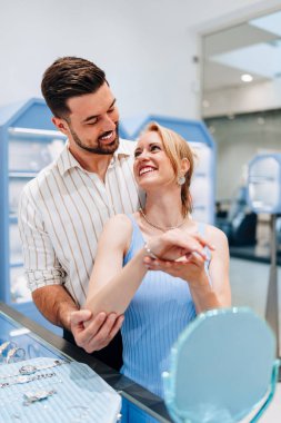 Mutlu genç çift kuyumcudan lüks mücevherler seçip almaktan zevk alıyor. Kadın mutlu ve heyecanlı.