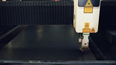 Endüstriyel CNC lazer kesme makinesi parlak kıvılcımlarla metal bir levhada delikler açıyor, fabrika ortamında modern otomatik üretim teknolojisi sergiliyor.