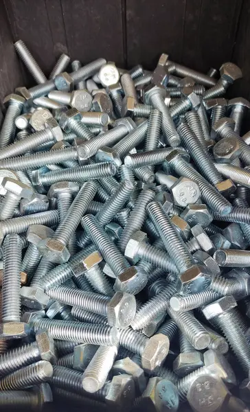 Tahta bir masanın üzerinde bir sürü vida var.