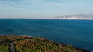 Gün batımında İzmir 'in panoramik hava manzarası. İzmir Körfezi 'nde feribot, kargo gemisi ve yelkenli..