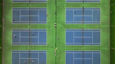 Mavi tenis kortlarının ve tenis oynayan insanların hava görüntüleri. Yukarıdan çekilen 4K 'lık yüksek kaliteli görüntüler, göz kamaştırıcı bir mavi kort olduğunu gösteriyor..