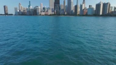 Michigan Gölü 'nden Chicago' nun panoramik manzarasına doğru destansı bir çekim, kamera suya yakın uçuyor ve yukarı doğru eğiliyor. Yüksek kalite 4k görüntü