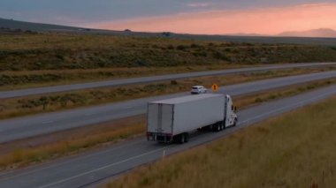Desert Steppe 'de yarı kamyon yolda duruyor. 4K görüntü. Çölün bozkırında gün batımında bir kamyonun görünümü yol boyunca ilerlemeye başlar. Ulaşım. Taşımacılık işi. Nakliye şirketi.