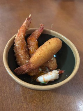 Lezzetli bir servis tabağı, içinde çıtır çıtır karides ve lezzetli soslu karides var, seramik kasede servis ediliyor. Çekici görünüşü ve dokusu onu deniz ürünleri aşıkları için ideal kılıyor..