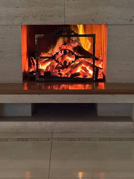 An elegant fireplace with dancing flames in a cozy, modern setting. The fire emits a warm glow, illuminating the stone walls and reflecting on the tile floor. Perfect for a relaxing night at home.