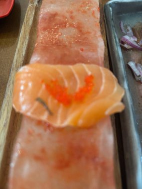 Tahta tabakta servis edilen taze, narin bir somon sashimi. Gümüş zemin ile somon kontrastının sulu dokusu ve canlı renkleri taze ve sofistike bir yemeği çağrıştırıyor..