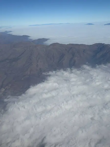 Uçsuz bucaksız açık mavi gökyüzü ile çelişen, beyaz bulutlarla kaplı dağların etkileyici hava manzarası. Görüntü arazinin doğal güzelliğini yakalıyor, vadileri ve tepeleri yumuşak bir sise bürünmüş. Kabarık bulutlar... 