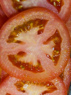 Taze domates dilimlerinde canlı, sulu bir doku görünür tohumlar ve koyu kırmızı bir renk bulunur. Sağlıklı, taze malzemelerin özünü yakalamak için mükemmel. Tazelik ve beslenme çağrıştırıyor..