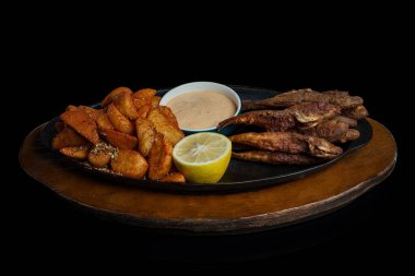 Kızarmış kırmızı kefal, Meksika patatesi, Meksika sosu ve siyah arka planda ahşap bir tabakta limon. Yüksek kalite fotoğraf