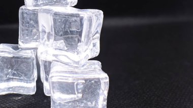 Işıl ışıl buz küpleri karanlık arka planda küçük bir piramit oluşturur, serinlik ve ferahlatıcı çağrıştırır..