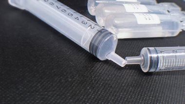 Şırıngalar ve ampuller koyu dokulu bir arka planda dizilmiş. Tıbbi tedavi, enjeksiyon ve doz konsepti.