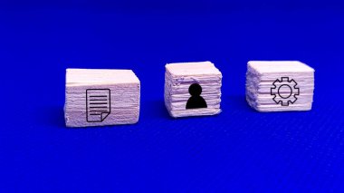 Süreci belge, kişi ve ayar simgeleri ile sembolize eden tahta bloklar, organizasyon, işbirliği ve sistem optimizasyonunu temsil ediyor.