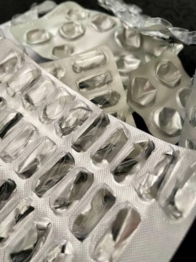 İlacın yokluğunu ortaya çıkaran berrak ve gümüş kabarcıklar gösteren boş ilaç paketlerinin detaylı bir yakın çekimi. Görüntü tüketim duygusunu ve bir & 39; 'un sağlığıyla ilgilenme rutinini anımsatıyor, ilaç, ilaç temalarını yansıtıyor