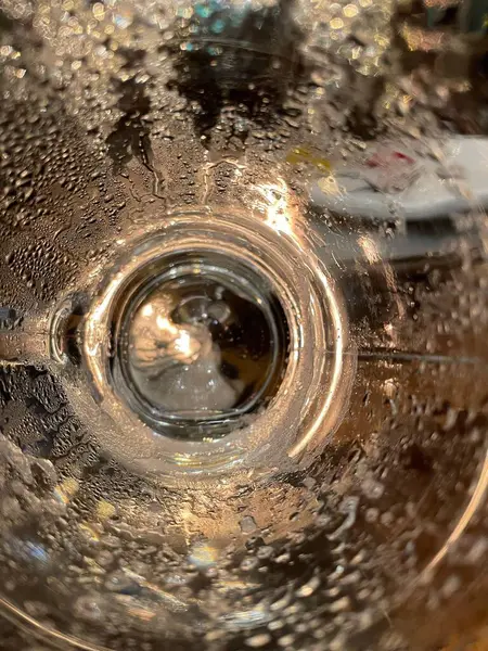 Su damlacıklarının bulanıklaştırdığı cam merkezinden manzarayı gösteren ilgi çekici bir görüntü. Işık yumuşak bir şekilde yansıyarak tazeliği ve ferahlığı çağrıştıran büyüleyici bir görsel efekt yaratır..