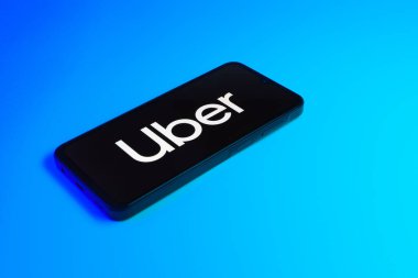 Prag, Çek: Mavi yüzey arka planında Uber logolu modern akıllı telefon aygıtı.