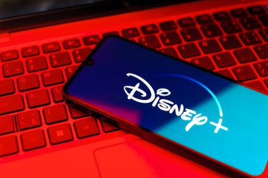Prag, Çek: Logo Disney + 'lı modern akıllı telefon ekranda ve arka planda dizüstü bilgisayar 