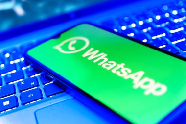 Prag, Çek Cumhuriyeti - 21 Ekim 2024: Laptop klavye arkaplanındaki modern akıllı telefon cihazı Whatsapp logosunu gösteriyor.