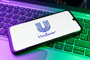 Prag, Çek Cumhuriyeti - 21 Ekim 2024: Laptop klavye arkaplanındaki modern akıllı telefon aygıtı unilever logosunu gösteriyor.