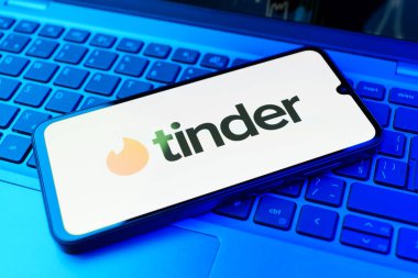 Prag, Çek Cumhuriyeti - 21 Ekim 2024: Laptop klavye arka planında Tinder logosu gösteren modern akıllı telefon aygıtı.